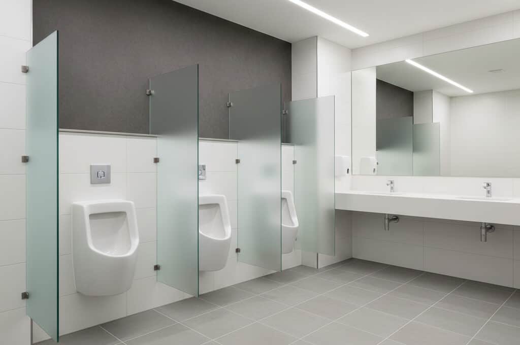 Urinal stalls and sinks in a modern public restroom, clean and well-lit.